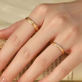 Hand wearing matte sunburst gold ring and trio-diamond gold ring on adjacent fingers